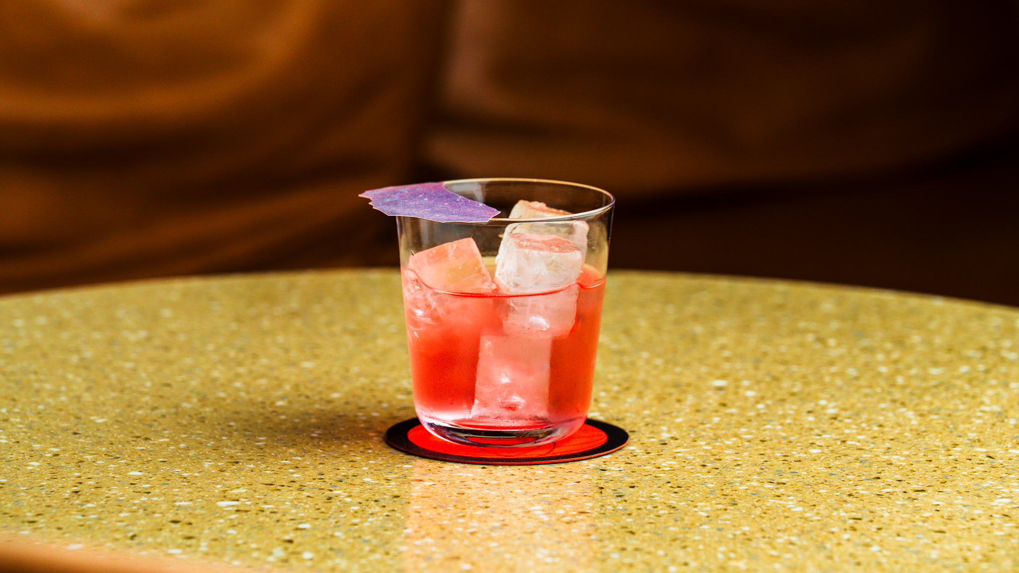 Cosy bar interior with warm lighting with focus on an elegant cocktail served over ice at Seed Library in Shoreditch.